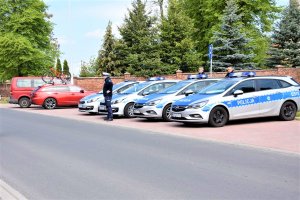 Cztery radiowozy na parkingu i policjanci uczestniczący w zabezpieczeniu.