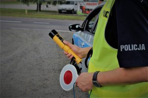 Policjant trzymający w ręce policyjny lizak i urządzenie do sprawdzania stanu trzeźwości