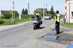 Policyjny motocykl mija stojącego na poboczu policjanta.