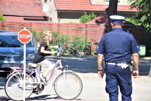 Uczeń pokonujący tor przeszkód pod okiem policjanta.