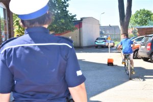 Uczeń pokonujący tor przeszkód pod okiem policjanta.