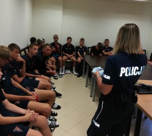 Policjantka przeprowadza spotkanie z młodzieżą podczas letniego wypoczynku.
