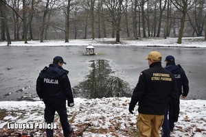 policjanci i strażak nad brzegiem wody