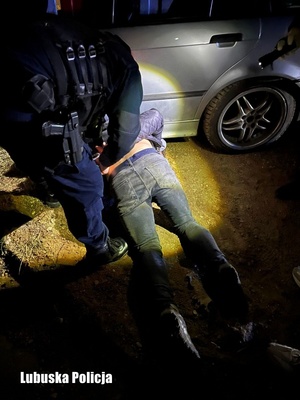 zatrzymany mężczyzna, skuty kajdankami  przez policjanta